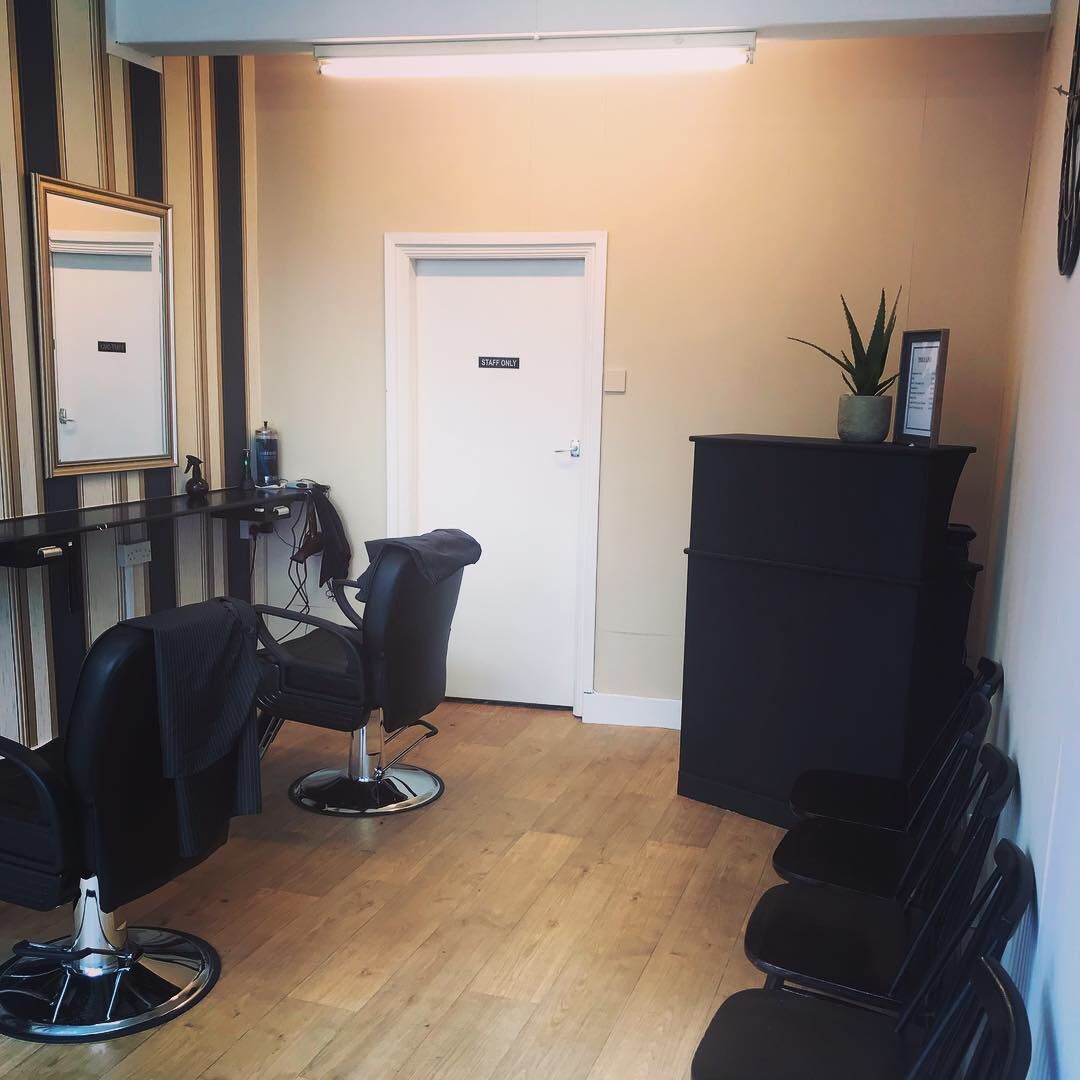 Two barber chairs in front of the mirrors and striped feature wall