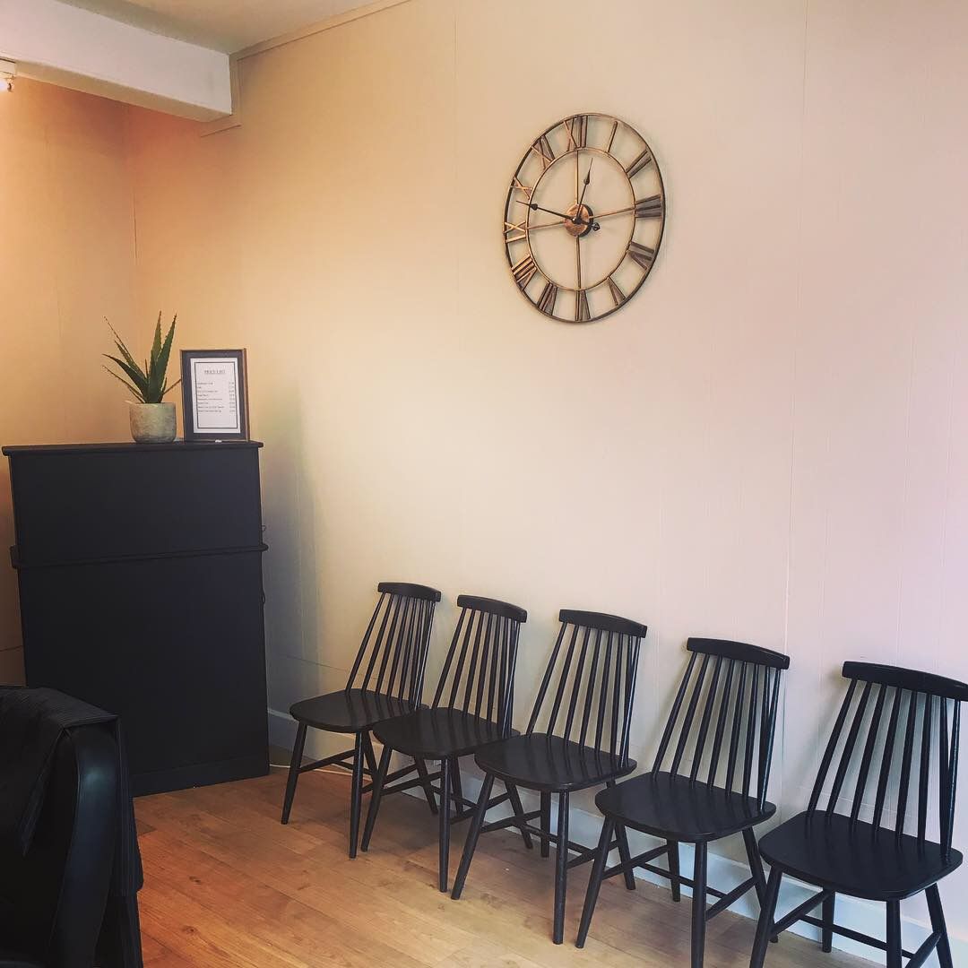The waiting area: a row of black spindle chairs under a large wall clock
